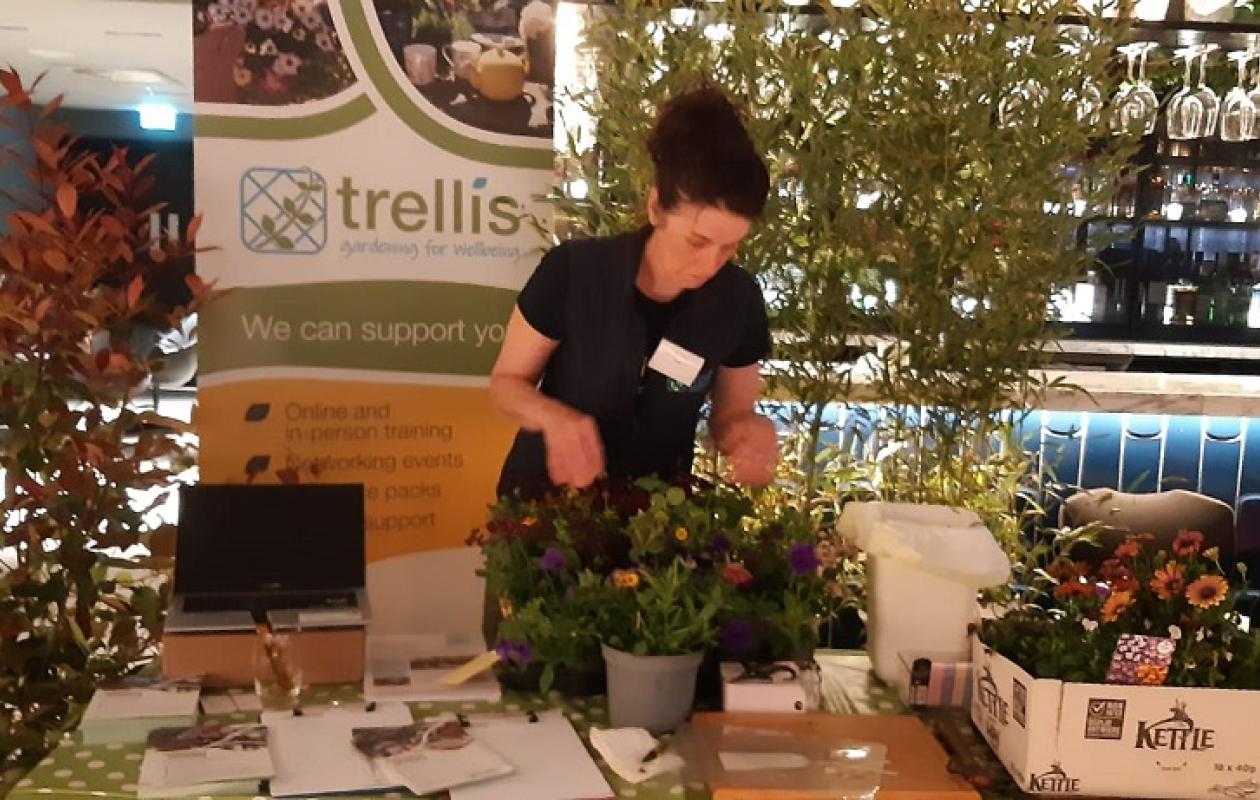 Trellis staff member at event stall surrounded by plants